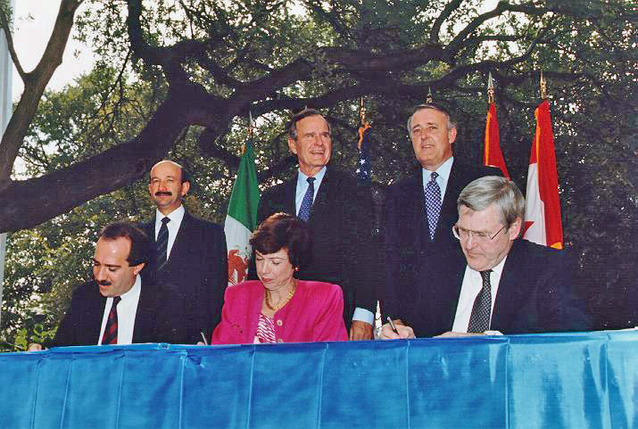 Carlos Salinas de Gortari, George H. W. Bush, and Brian Mulroney standing behind their trade ministers at the NAFTA initialing ceremony